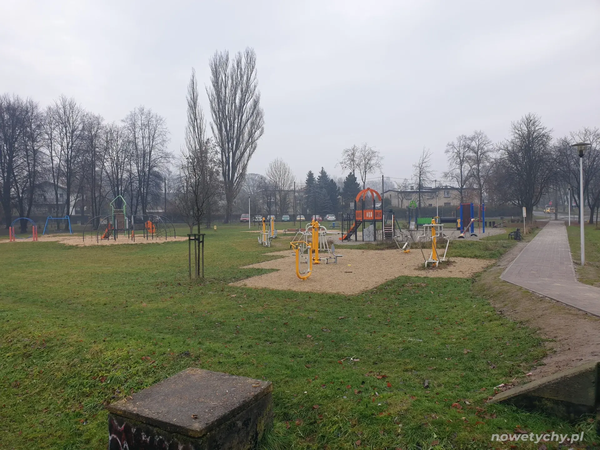 W tle plenerowa siłownia oraz plac zabaw