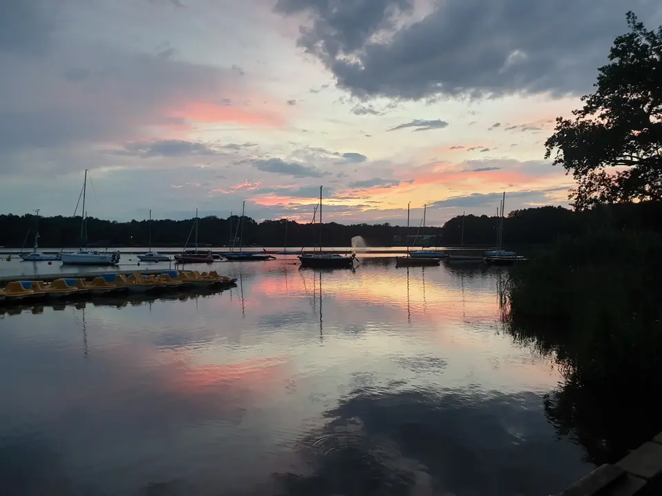 Widok na zacumowane żagl&oacute;wki i rowerki wodne - po zachodzie słońca